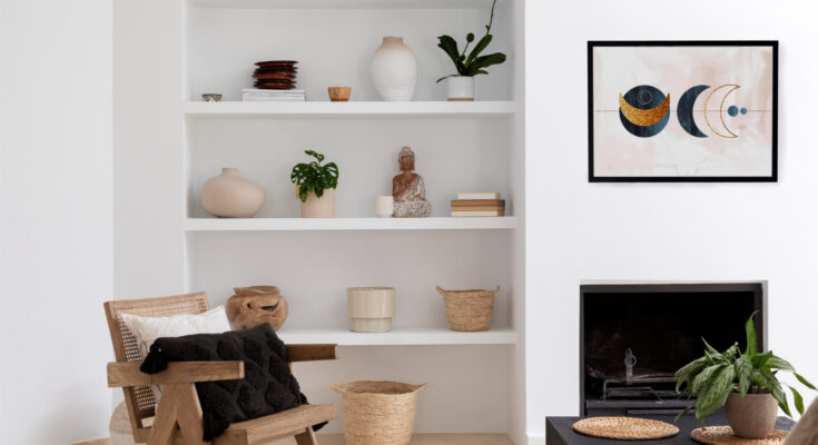 Salon moderne à la décoration épurée avec une étagère murale d'objets artisanaux, un fauteuil en rotin et un cadre décoratif