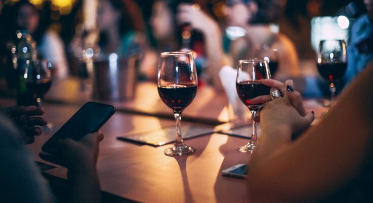 Des verres de vin rouge posés sur la table d'un bar animé durant une soirée conviviale entre amis.