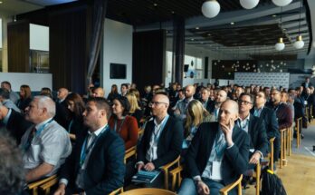un public attentif assis dans une grande salle de conférence écoutant une présentation lors d'un événement professionnel