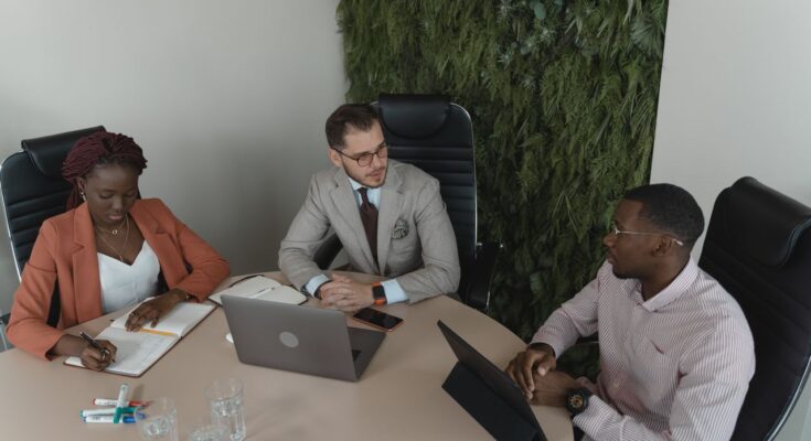 Une équipe de collaborateurs réunis autour d'une table ronde lors d'une réunion de travail dans un bureau moderne.