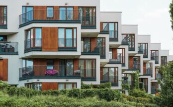 Façade d'un immeuble résidentiel moderne aux balcons décalés avec finitions en bois et éléments végétalisés.