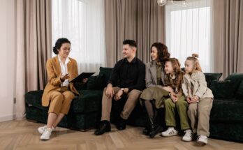 Une conseillère financière échange avec une famille de quatre personnes installée sur un canapé dans un salon moderne